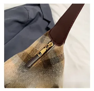 Gros plan sur la fermeture éclair dorée d'un sac à carreaux vintage avec bandoulière