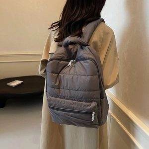 Detailed view of grey quilted nylon backpack with padded straps and zipper compartments