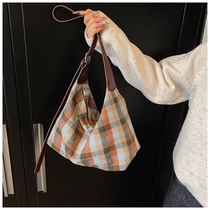 Détail du sac hobo à carreaux vintage avec poignée en cuir marron et fermeture éclair