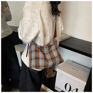 Détail d'un sac hobo à carreaux texturé avec bandoulière en cuir et couleurs d'automne