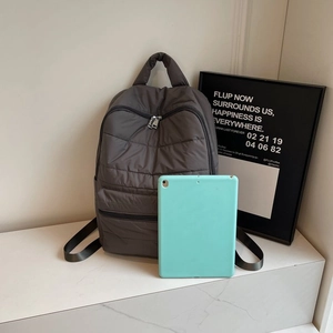 Detail of quilted nylon backpack featuring zipper closure and tablet storage capacity