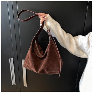 Texture détaillée du cuir dépoli marron foncé sur un sac hobo minimaliste en demi-lune