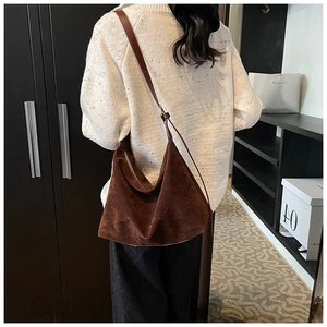 Détail d'un sac hobo en daim marron avec bandoulière réglable porté par un modèle