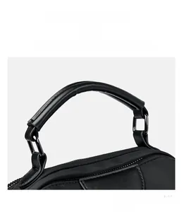 Detail of reinforced stitching on the ergonomic nylon bag handle with matte metal hardware
