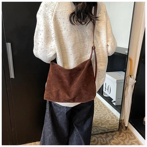 Sac bandoulière en suédine marron foncé montrant la texture souple et la forme demi-lune