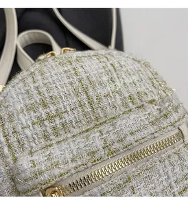 Dettaglio del tessuto tweed bianco con fili dorati e cerniera in metallo dorato