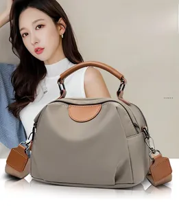 Close-up of contrast stitching detail and brown leather handle on nylon tote bag