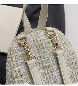 Dettaglio del tessuto in tweed con fili dorati e finiture in oro chiaro della borsa
