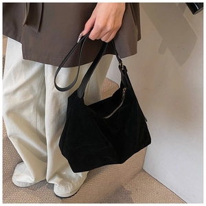 Détail du sac hobo en daim noir avec fermeture éclair dorée et texture mate élégante