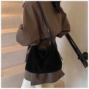 Détail du sac hobo noir mat à l'épaule, style bandoulière minimaliste et décontracté