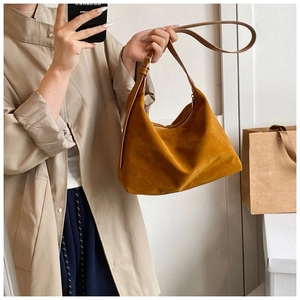 Détail d'un sac à bandoulière marron mat au design trapézoïdal et épuré