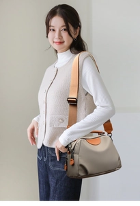 Close-up of beige nylon shoulder bag featuring contrast stitching and wide woven strap