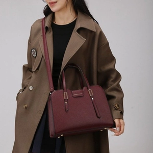 Chic burgundy lychee texture crossbody bag with top handle worn with a trench coat