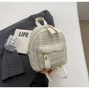 Dettaglio di mini zaino in tweed bianco e oro con spalline in pelle e cerniera in metallo oro