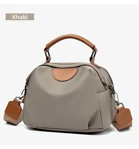 Detail view of khaki nylon handbag with contrast stitching and brown faux leather handle