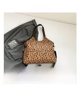 Detail view of leopard print tote bag with brown straps and golden metal buckles