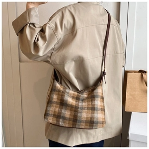 Modèle portant un sac bandoulière vintage à carreaux avec des motifs marron chauds