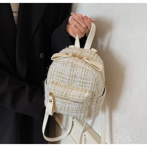Dettaglio mini zaino in tweed con cerniere dorate e decorazione a fiocco bianco