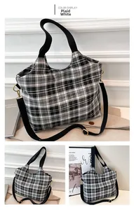 Detail of checkered canvas tote bag showing black fabric straps and gold metal hooks