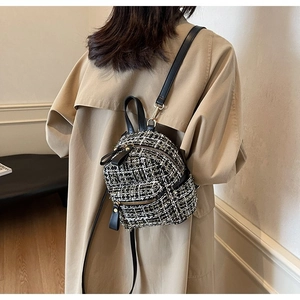Dettaglio ravvicinato della trama in tweed bianco e nero e della cerniera dorata della borsa