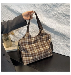 Detailed shot of brown plaid fabric tote bag with sturdy straps and golden metal hardware