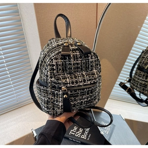 Dettaglio del mini zaino in tweed bianco e nero con cerniere dorate e manico in pelle