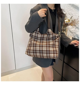 Detail of checkered tote bag with wide brown strap and gold metal hardware