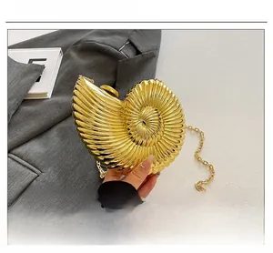 Detailansicht der goldenen Acryl-Clutch in Muschelform mit metallischer Textur