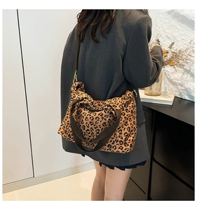 Detail of leopard print tote bag with thick strap shown on a model in gray blazer