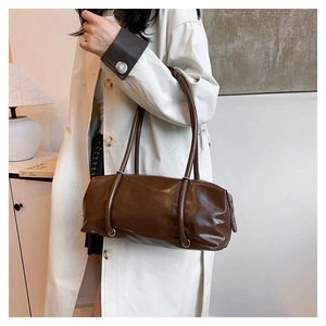 Detail of dark brown cylindrical PU leather bag with glossy finish and dual thin straps