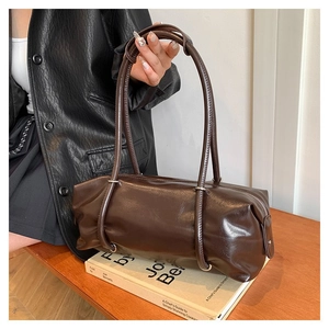 Detail of a dark brown glossy PU leather cylinder Boston bag with silver buckles