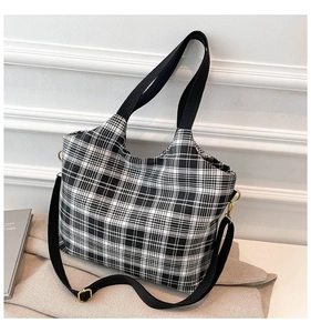 Detail of checkered tote bag with golden metal buckle and adjustable black strap
