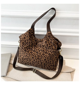 Detail of leopard print tote bag with brown straps and golden hardware in a lifestyle setting