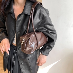 Detail of dark brown glossy PU Boston bag showing cylindrical shape and retro stitching