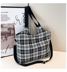 Detail of black and white checkered tote bag with adjustable strap and gold metal hardware