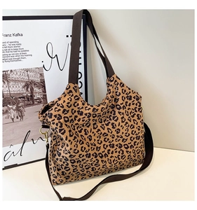 Close-up of leopard print tote bag with brown nylon strap and golden metal buckle