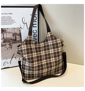 Close-up of brown and white checkered canvas tote with dark brown strap and gold metal buckle