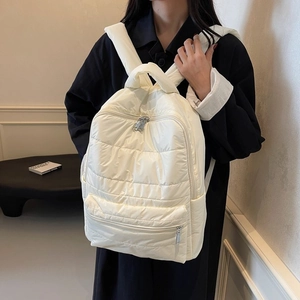 White quilted nylon backpack with padded texture and silver zippers on model