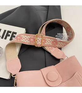 Detail of pink bucket bag with colorful embroidered strap and golden adjustable buckle