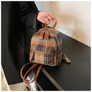 Detail van vintage geruite rugzak met wollen textuur en leren bandaccenten