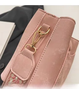 Detail of pink faux leather bag showing golden metal hook and woven jacquard strap