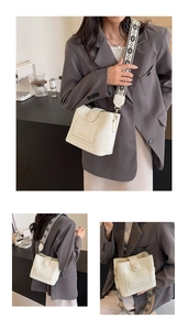 Detail of off-white bucket bag with geometric wide strap and decorative stitching