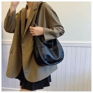 Minimalist black leather hobo bag with stitching detail worn by model in brown blazer