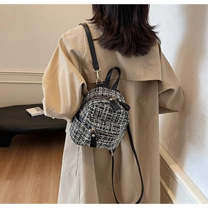 Mini zaino alla moda in tweed bianco e nero con spalline in pelle su trench beige chic