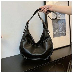 Detail of black leather hobo bag featuring fine stitching and gold hardware accents