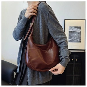 Detail of dark brown crescent shoulder bag with stitching and adjustable leather strap