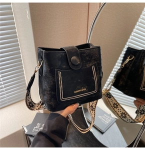 Detail of black bucket bag with bohemian wide strap and white dotted pocket texture