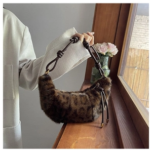 Leopard print faux fur crescent bag with knotted rope handle shown in a cozy setting