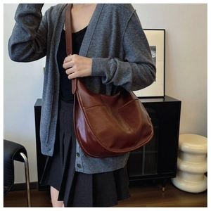 Detailed view of dark brown saddle handbag with decorative stitching on polished faux leather