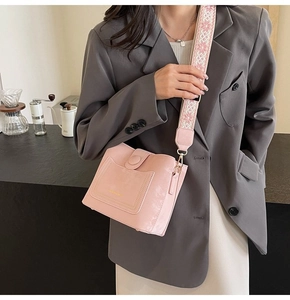 Detailed shot of pink leather bucket bag with geometric embroidered wide strap
